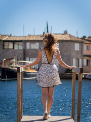 A beautiful girl stands on a pier in the Marina of Port Grimaud, France. Sunny day, clear sky