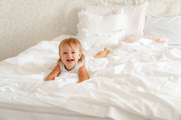 little girl on bed in bedroom and laughs. happy childhood.