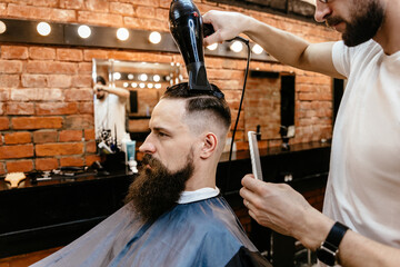 Barber drying male hair in hairdressing salon
