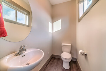 Bathroom of home with free standing sink round mirror toilet and wooden floor