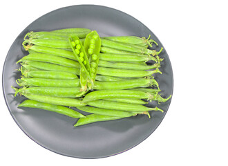 Peas in a pod, lies on a plate, isolate. Green peas for cooking veggie food. Green beans on a black plate.