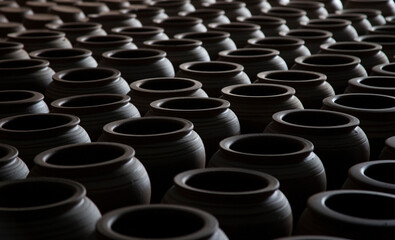 Hundreds of handmade pots in the workshop. Shadow and light together.