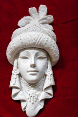 Sculpture of a mask. Mask of a human face made of gypsum on a red surface. Beauty, skin care and masquerade concept.