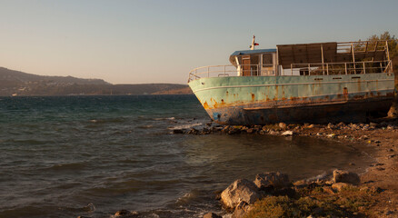 Shipwreck at the beach waiting for the repair in summer season during sunset time. Ship is pulled...