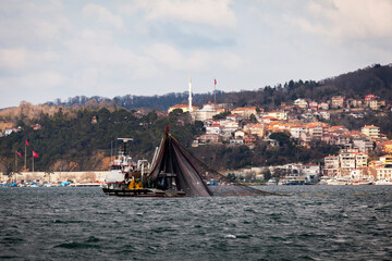 Fishing boat pulling the net and catching the fishes in Istanbul marmara sea with cityscape...