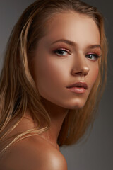 Obraz premium Closeup face fashion beauty portrait of young beautiful caucasian blonde woman with straight hair and makeup posing against gray background.
