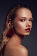 Fototapeta premium High fashion closeup beauty portrait of young stunning woman with long straight blonde hair, perfect makeup and red lips against gray background