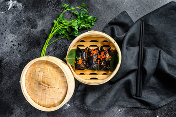 Obraz na płótnie Canvas Black Dim sum dumplings in bamboo steamer. Asian cuisine. Black background. Top view