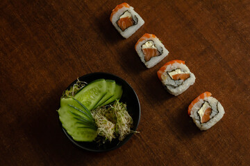 Sushi uramaki com salmão cru e cream cheese acompanhado de salada de pepino e broto de feijão