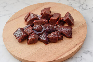Beef liver lies on a wooden Board and a light background, raw meat