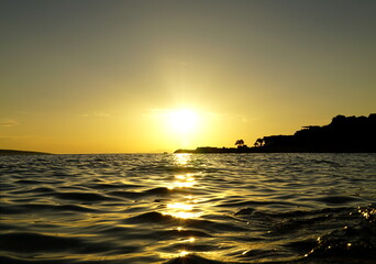 Fototapeta na wymiar Shining sun above the sparkling sea water surface at sunset