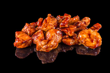 Delicious teriyaki chicken pieces with reflection, isolated on black background