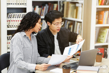Couple discussing charts and diagrams in library