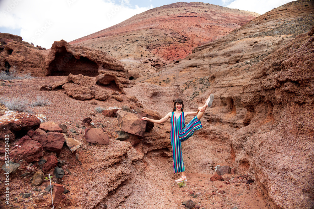 Wall mural young woman stretching in a volcanic landscape during summer holiday