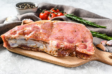 raw pork chop steak on a wooden chopping Board. Gray background. Top view