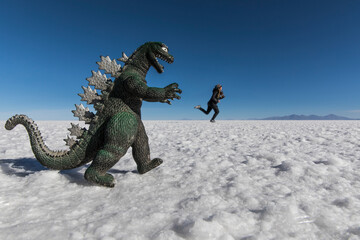 Woman playing in salt flats escaping from dinosaur