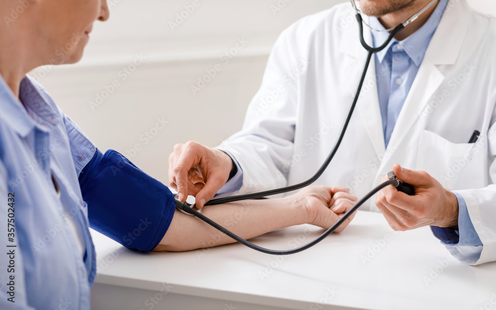 Wall mural doctor checking blood pressure of senior patient during visit