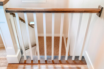 U shaped stairway of home with brwon handrail supported by white balusters