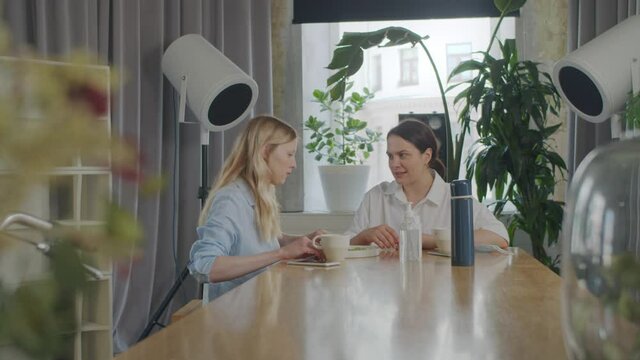 Two beautiful lesbian girls, sitting at table in cafe, feed each other food, communicate and laugh, girls hug, hold hands. Lgbt