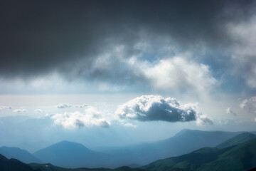 Summer rain in the mountains. Dramatic clouds and mountains silhouette. Lonely cloud