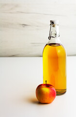 Apple cider, vinegar, juice in a glass bottle on a light background