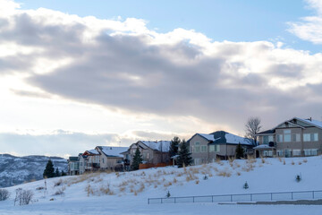 Clouds and blue sky over homes on pristine terrain of Wasatch Mountains