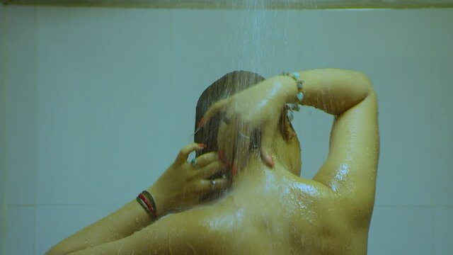 Brunette Indian Woman Washing Hair In The Shower. Closeup. View From Back. Back View Of Hot Woman Posing On Camera In Bathroom.