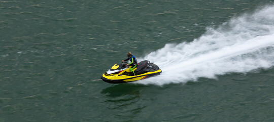 Yellow jetski moving very fast leaving white trace behind it. Close shot. Sports / competition concept. Aerial view.