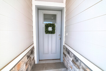 Square leafy wreath on front door entrance with glass pane and transom window