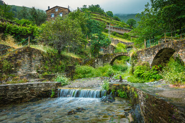 Fototapeta na wymiar Moutain river with stone bridge and waterfalls with beautiful vegetation in Piodao, Aldeias de Xisto, Portugal