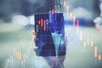 Double exposure of forex chart sketch hologram and woman holding and using a mobile device. Financial market concept.