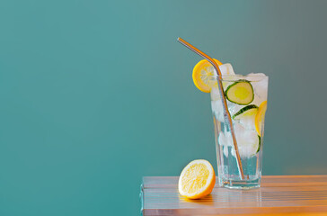 Refreshing tonic and gin Tom Collins cocktail or lemonade with lemon ice and cucumber on contrast colorful blue and yellow background. Bar menu, alcohol recipe decor, specialized website blog design