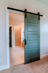 Sliding gray wooden panel door that leads to the bathroom of a home