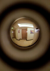 A corridor, lamps, a floor and two neighboring doors are visible in the door peephole