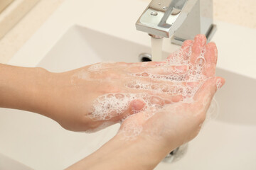 Woman washing hands with antiseptic soap in bathroom, closeup