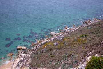 Fototapeta na wymiar Rocks in the crystal clear blue sea of ​​Nazaré beach , Portugal