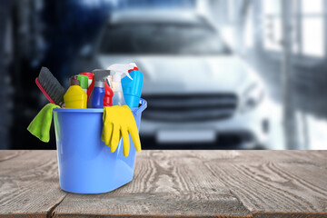 Bucket with cleaning supplies on wooden surface at car wash. Space for text