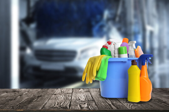 Bucket With Cleaning Supplies On Wooden Surface At Car Wash. Space For Text