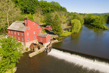 Aerial of an old red mill with a waterfall on a lake. © ChristyLangPhotos