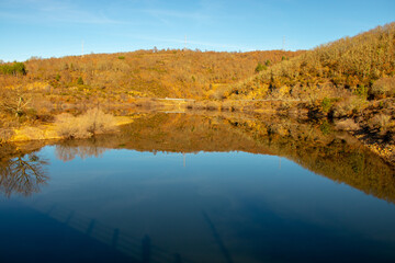 Stunning photo of autumn colors reflected on a lake with a glass like mirror water surface , Spain
