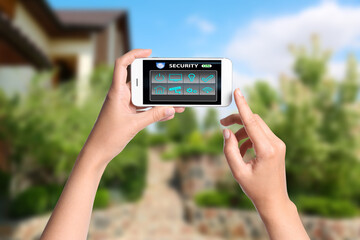 Woman monitoring modern CCTV cameras on smartphone near her house, closeup. Home security system
