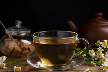 Delicious chamomile tea in glass cup on wooden table