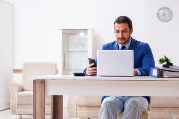 Young male employee working from house in self-isolation concept