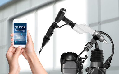 Engineer controlling electronic laboratory robot manipulator with smartphone indoors, closeup. Machine learning