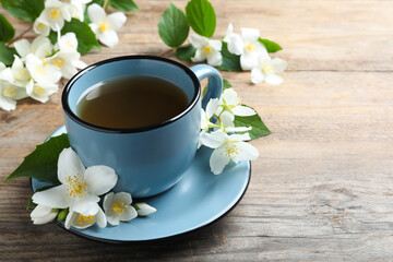 Cup of tea and fresh jasmine flowers on wooden table