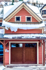 Brown wooden glass panelled garage door of home under snowy roofs in winter