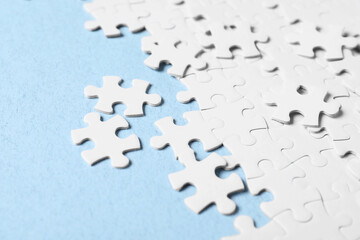 Blank white puzzle pieces on light blue background