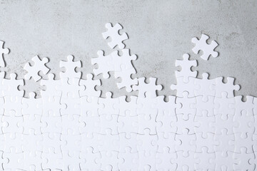 Blank white puzzle pieces on light grey stone background, flat lay