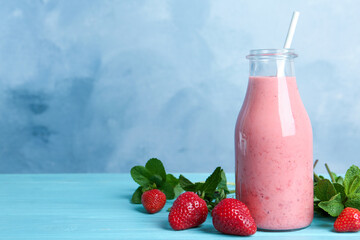 Tasty strawberry smoothie and mint on light blue wooden table. Space for text