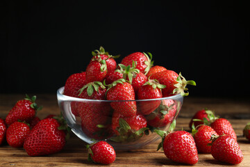 Delicious ripe strawberries in glass bowl on wooden table